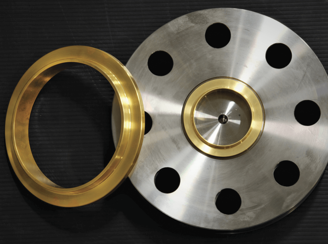 A shiny metallic disc with evenly spaced circular holes and a gold-colored ring placed next to it, set against a dark, textured background.